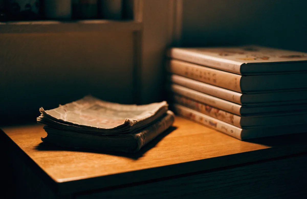One battered, dog eared book on a desk beside a neat stack of intact ones.